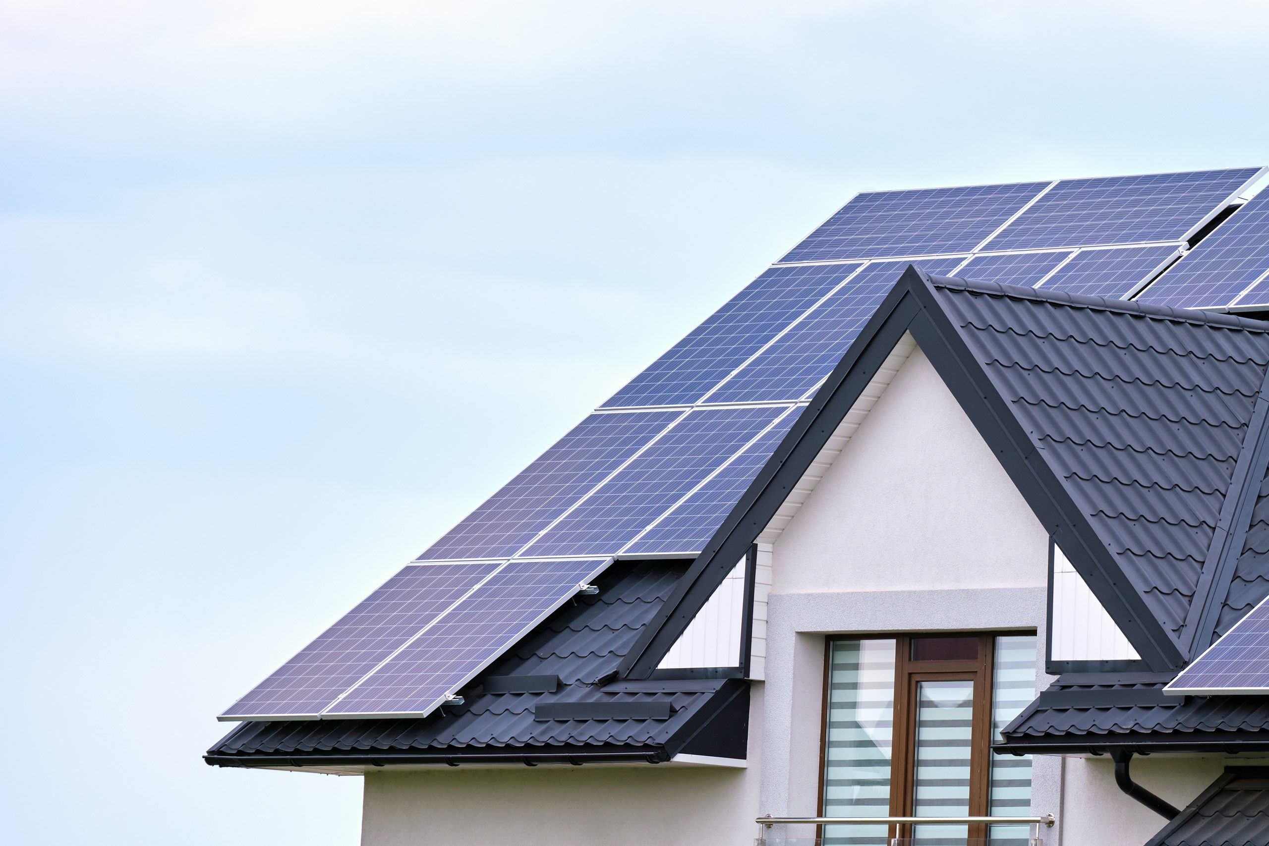 Residential house with solar panels on the roof against a blue sky