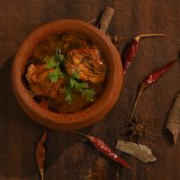 Kerala chicken curry in a clay pot with dried red chillies