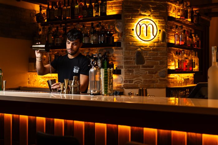 A bartender mixing cocktails at a warmly lit bar