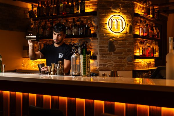A bartender mixing cocktails at a warmly lit bar