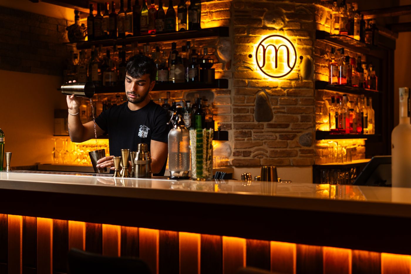 A bartender mixing cocktails at a warmly lit bar