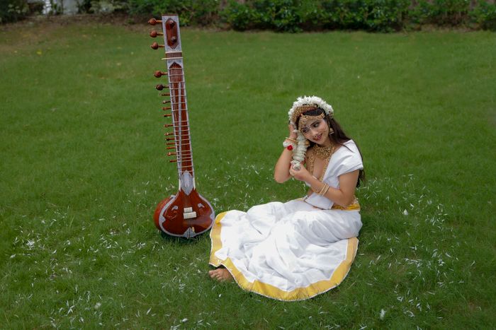 A musician with a veena on the lawn