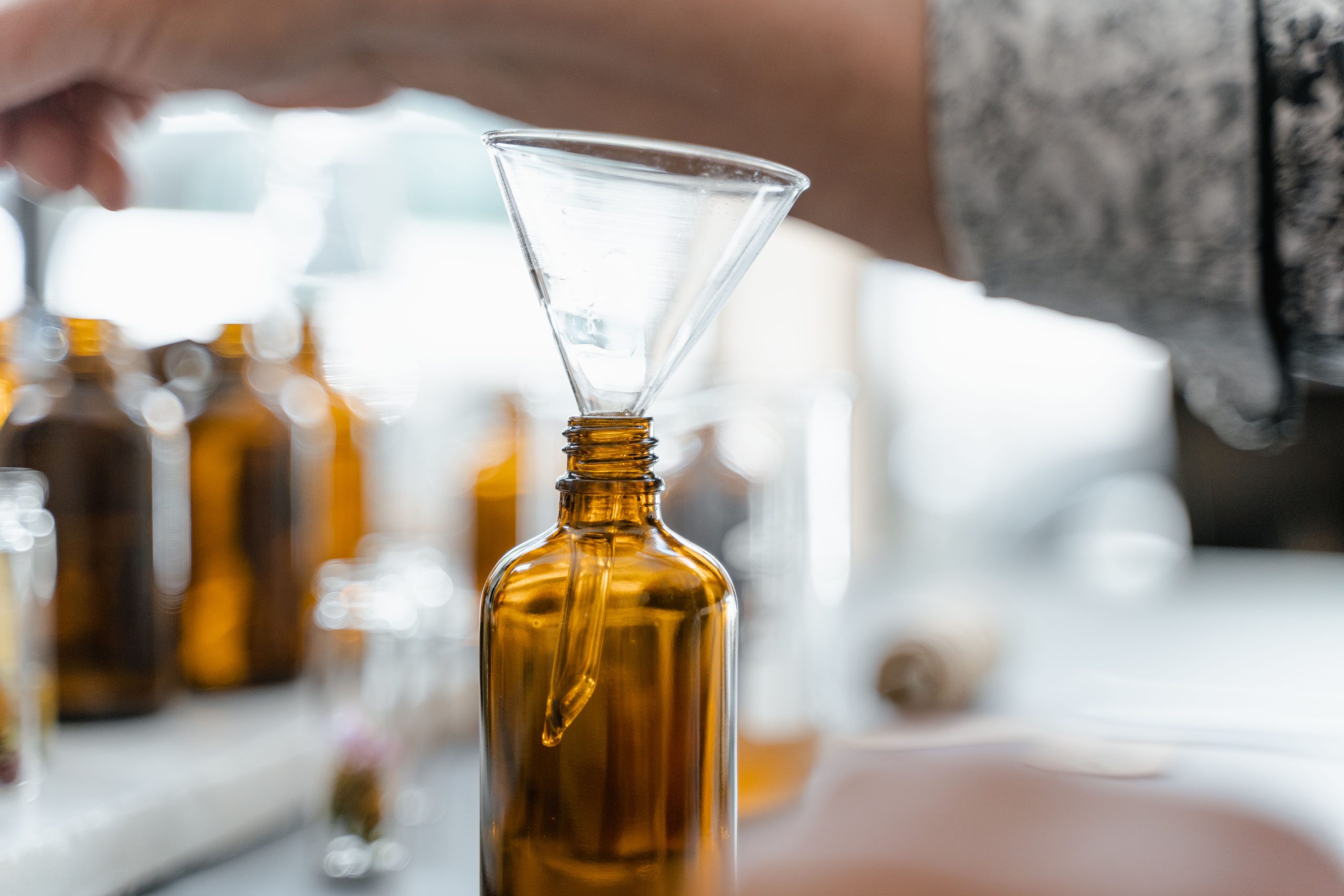 A glass funnel in an amber bottle on a bench of small bottles