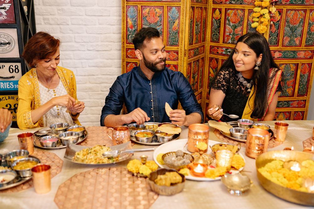 Friends celebrating over a table of Indian dishes